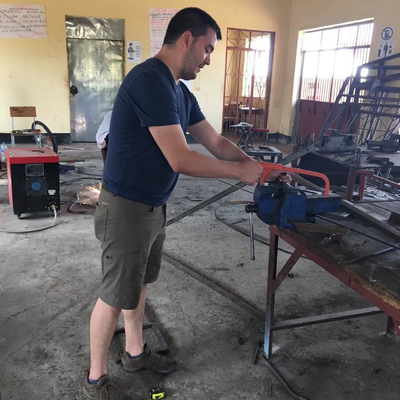 Kyle Reeser helping out in the metal shop at LVDC.  The Lake Victoria Disability Centre Campus consisted of many yellow buildings with corrugated metal roofs, all built and maintained by LVDC staff.  Lake Victoria Disability Centre | Musoma, Tanzania.