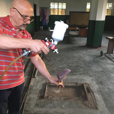 Roberto Postelmans spraying a piece of foam with an Ottobock Superskin coating for cosmetic purposes.  HVP-Gatagara | Gatagara, Rwanda.  